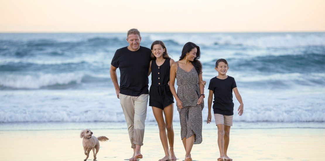 Parents with their two children and dog on the beach walking towards camera - Tisser Law Group