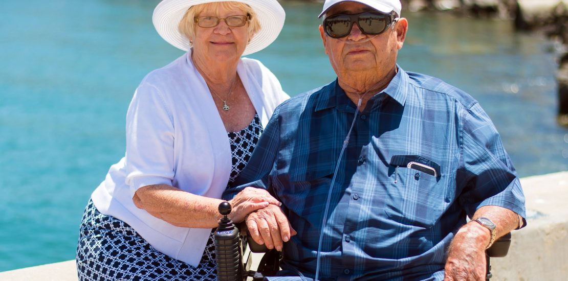 Elderly retired couple smiling at the camera near a body of water - Tisser Law Group Planning for IRAs and Other Retirement Assets